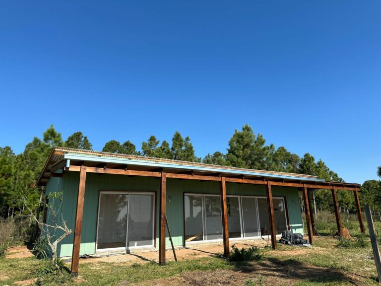 Casa con revestimiento de durlock y vigas a la vista. Aberturas blancas. Piso de madera. Revestimiento de sidding